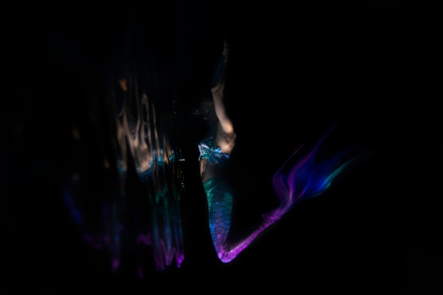 A woman in a mermaid costume swims underwater.