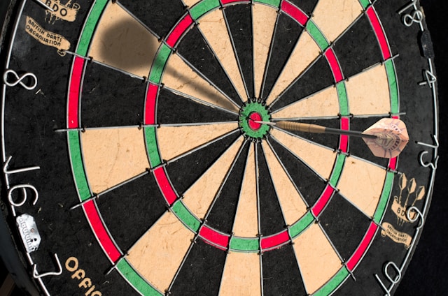 A dart hits the dart board’s bull’s eye.