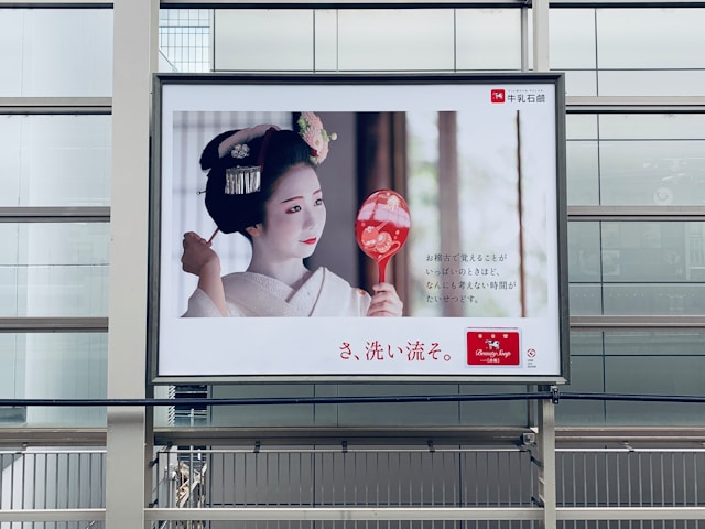 An ad display features a Japanese woman wearing heavy traditional makeup.