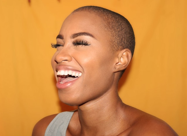 A beauty influencer models makeup products and laughs for the camera.