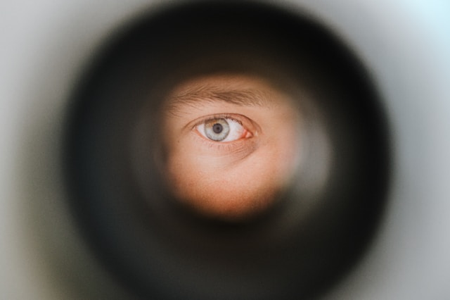 A person’s eye peeks through a camera lens.
