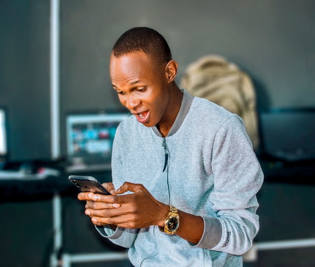 A man looks excited as he looks at his phone.