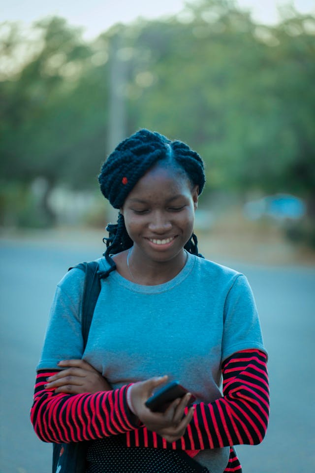A woman looks down at her cell phone and smiles.