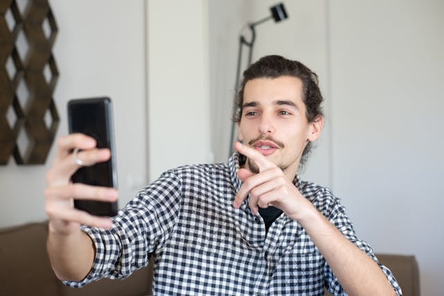 A man talks to a phone that he holds in one hand.