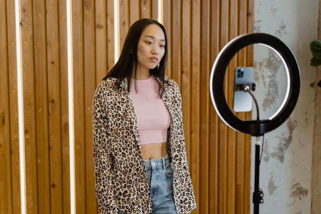 A woman vlogs in a leopard print shirt.