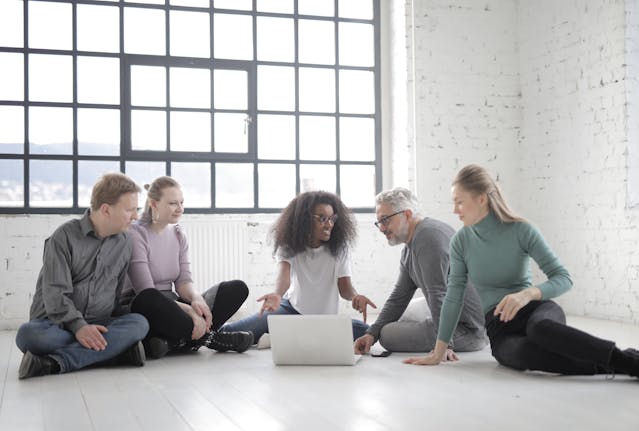 A group of people gather around a laptop.