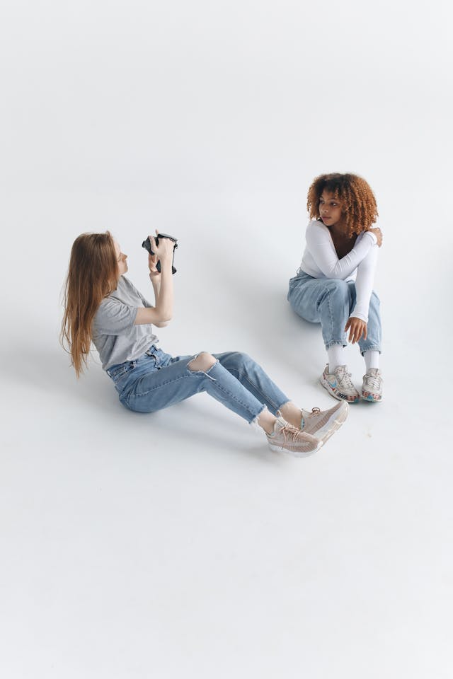 A woman points a camera at another woman.