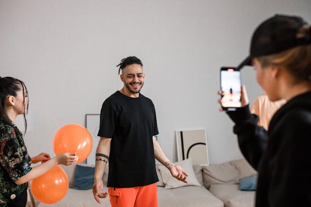 A woman records a man and woman with balloons.
