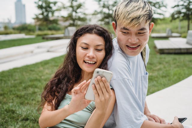A woman laughs as she shows her phone to a man.