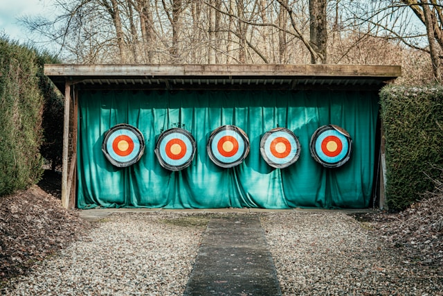 Multiple archery targets are lined up on a wall.