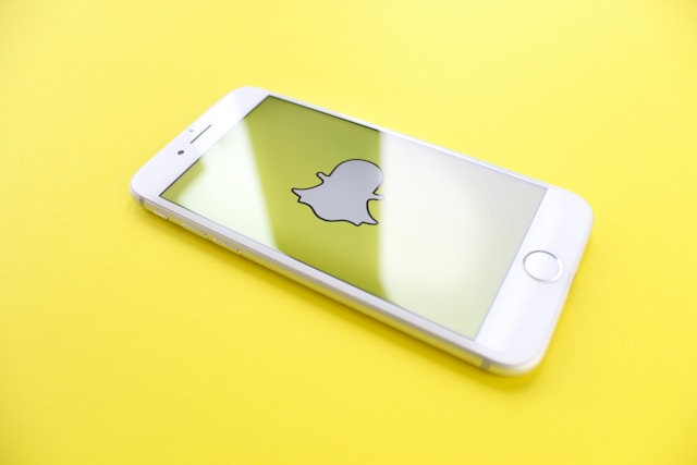 A phone screen displays the Snapchat ghost icon.