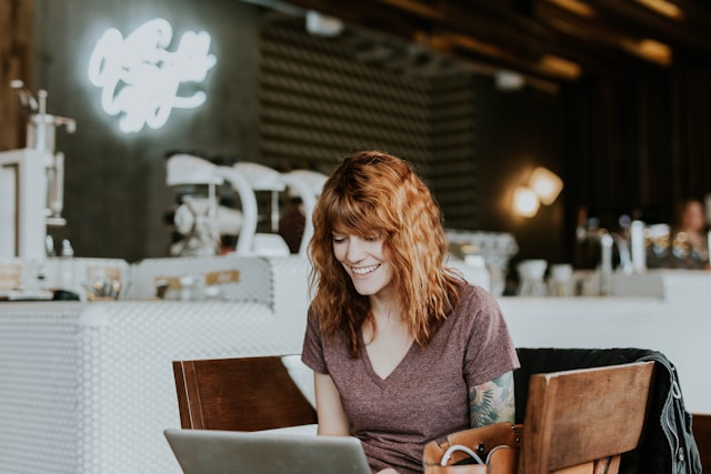 A woman wears a big smile while she looks at her TikTok earnings on her laptop.