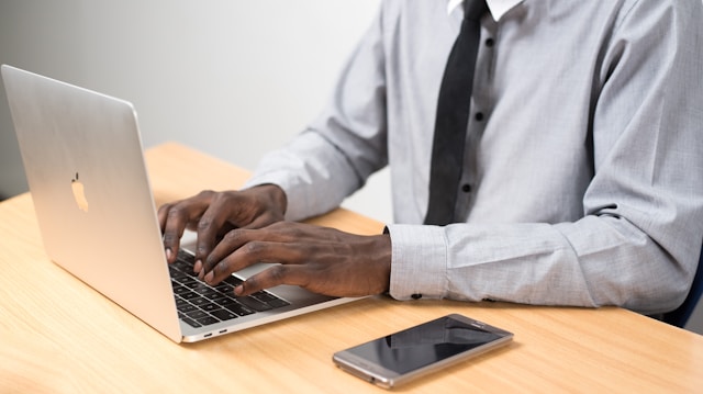 A man in a tie types comments on his laptop.