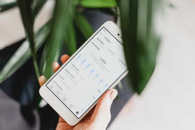Someone holds a phone that shows their social media insights on the screen.