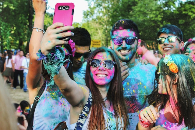 A group of young people with paint on their faces takes a photo together.
