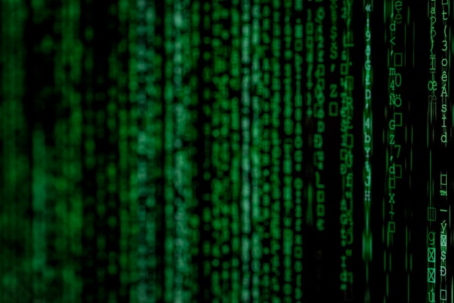 A black computer screen displays rows of code.