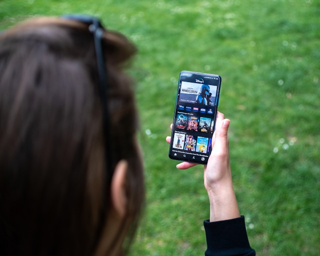 A woman browses video collections on her favorite streaming service on her phone.