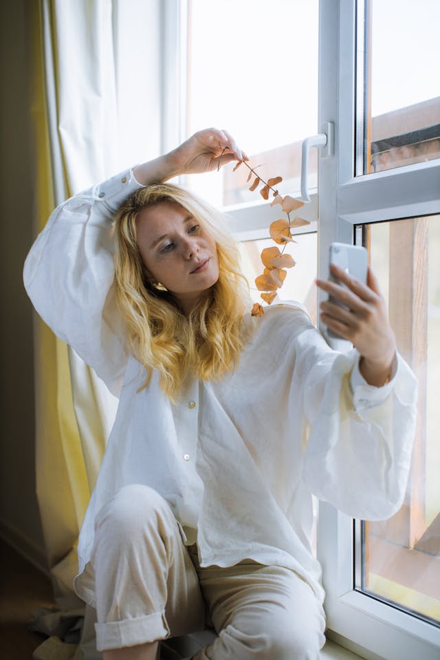 A woman takes a selfie with a plant.