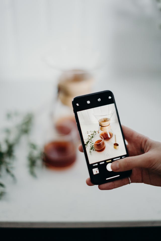 A person takes a photo of a coffee and a teacup.