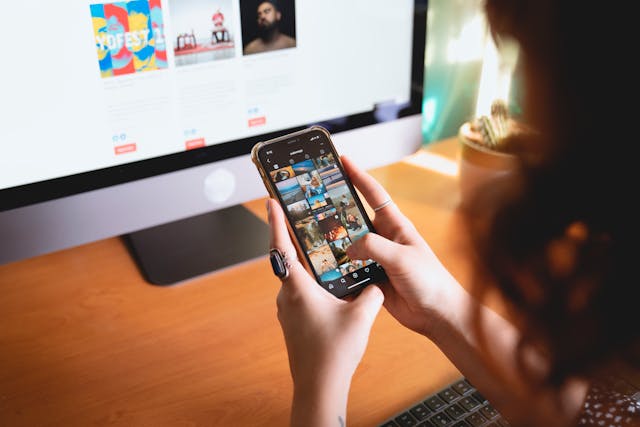 A person swipes through photos in front of a desktop computer.