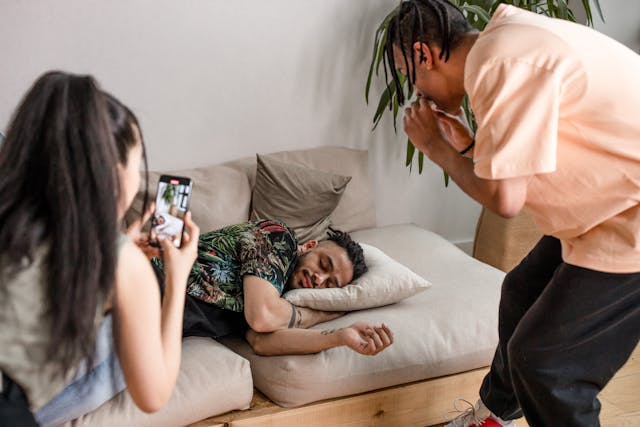 Two people record a man while he sleeps.