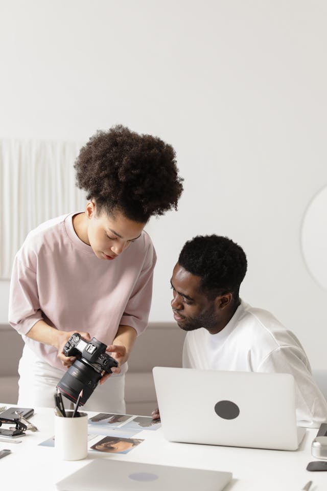 A woman shows the image on her camera to a man.