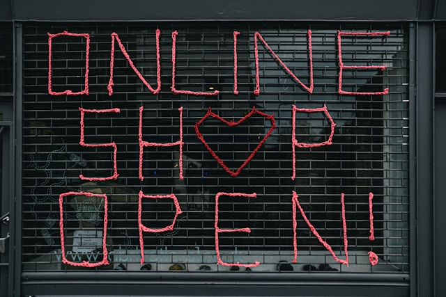 A sign on a store window reads, “Online shop open.”