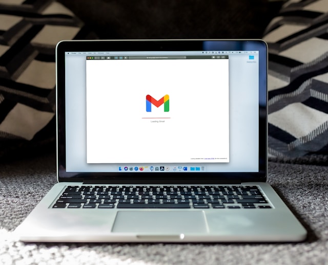 A laptop screen displays the Gmail logo as the email tool loads.