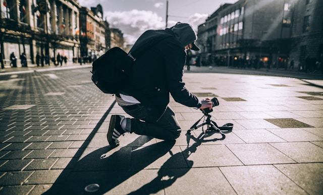 A creator sets up their video camera on the ground in the middle of an empty street.