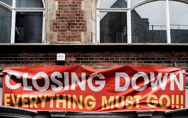 A big banner on the side of an old brick building says, “Closing down, everything must go.”