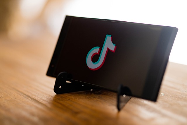 A smartphone on a table stand displays the TikTok logo on its screen.