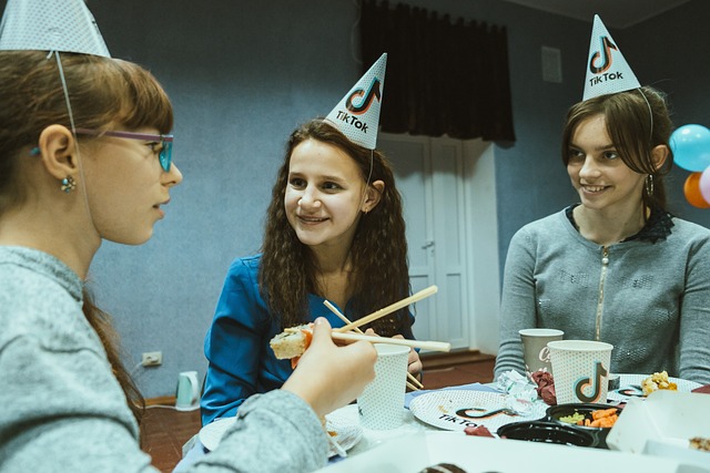 Three people with TikTok-themed hats enjoy dinner at a table.