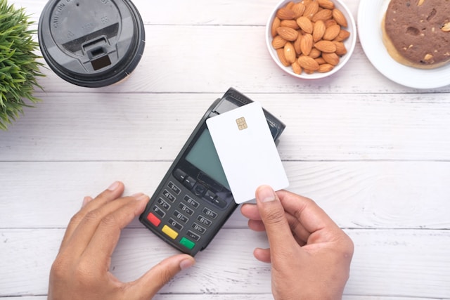 A person swipes their card against a portable POS machine.