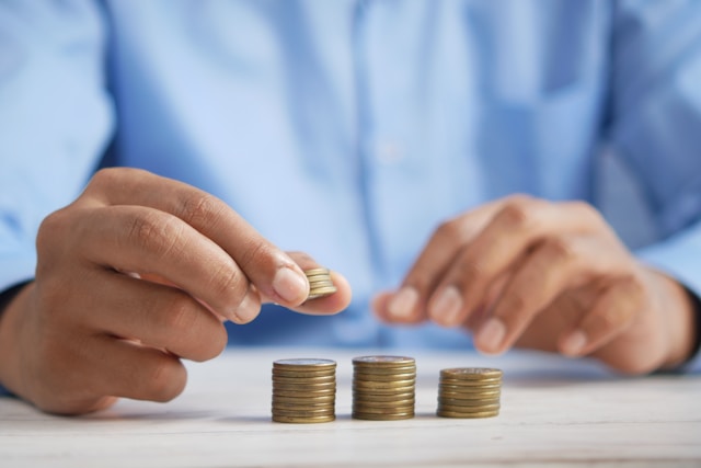 A person stacks coins on a table.