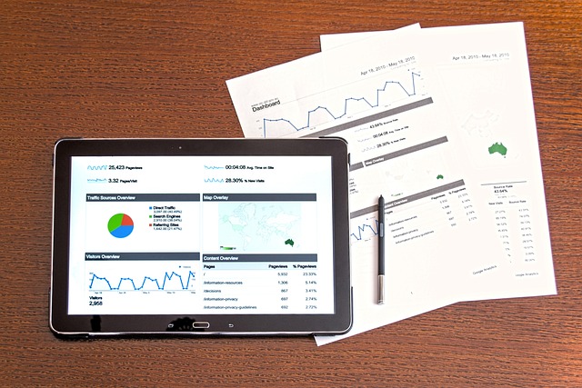 A tablet and several printed papers on a table display multiple charts and graphs.