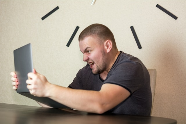 A person looks angry as they grab their laptop.