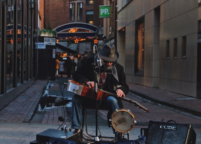 A male busker sets up his music equipment at the entrance to an alley.