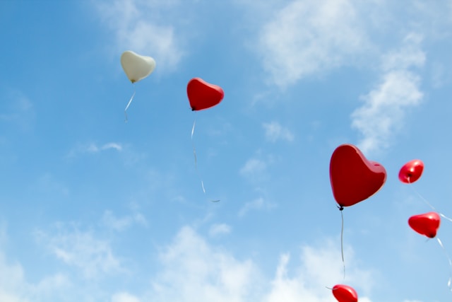 Red and white balloons are floating in the sky.