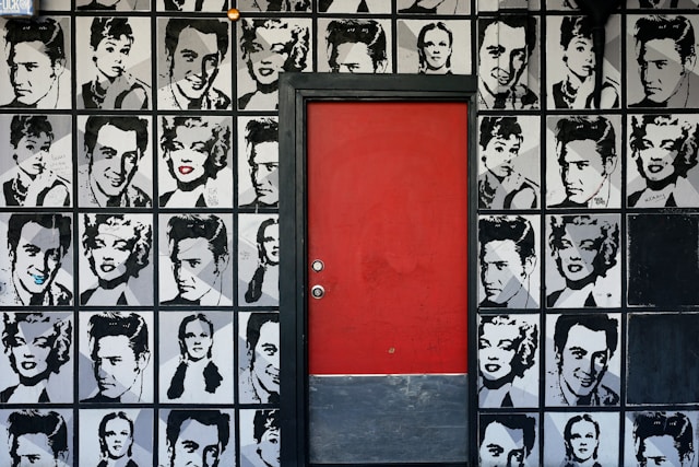 A red door is set against a wall featuring classic Hollywood celebrities.