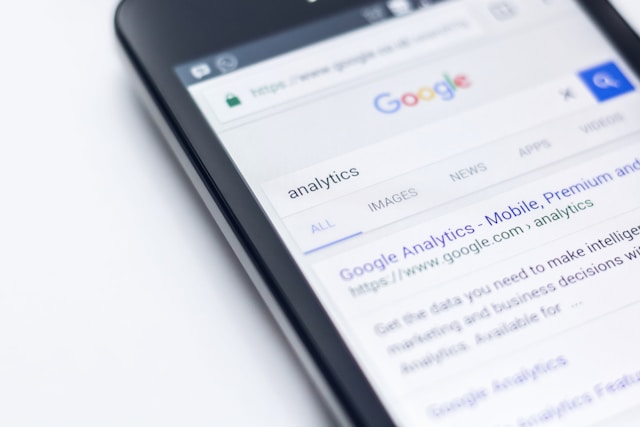 A person holds a phone and shows the Google search results for the word “Analytics.”