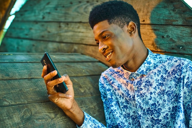 A man smiles as he watches TikTok videos on his phone.