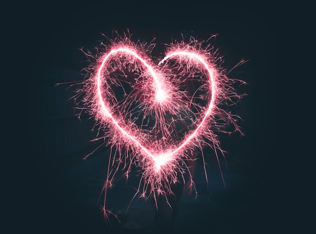 A red sparkler forms the shape of a heart.