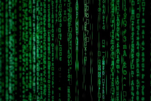 A black digital screen displays lines of green computer code.