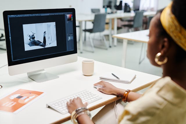 A woman edits a video on her desktop computer.