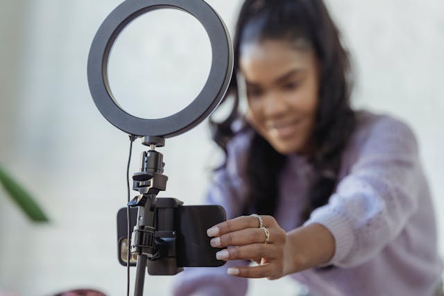 A person records a video of themself on a phone attached to a stand.