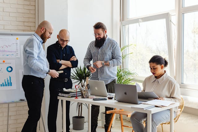 Colleagues work together in an office using their laptops.