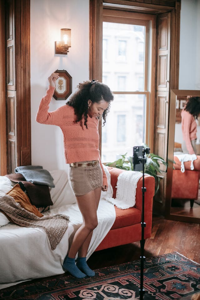 A phone on a tripod records a woman showing off clothes.