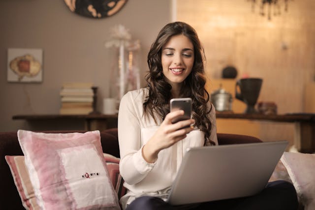 A woman stares at her phone and grins.