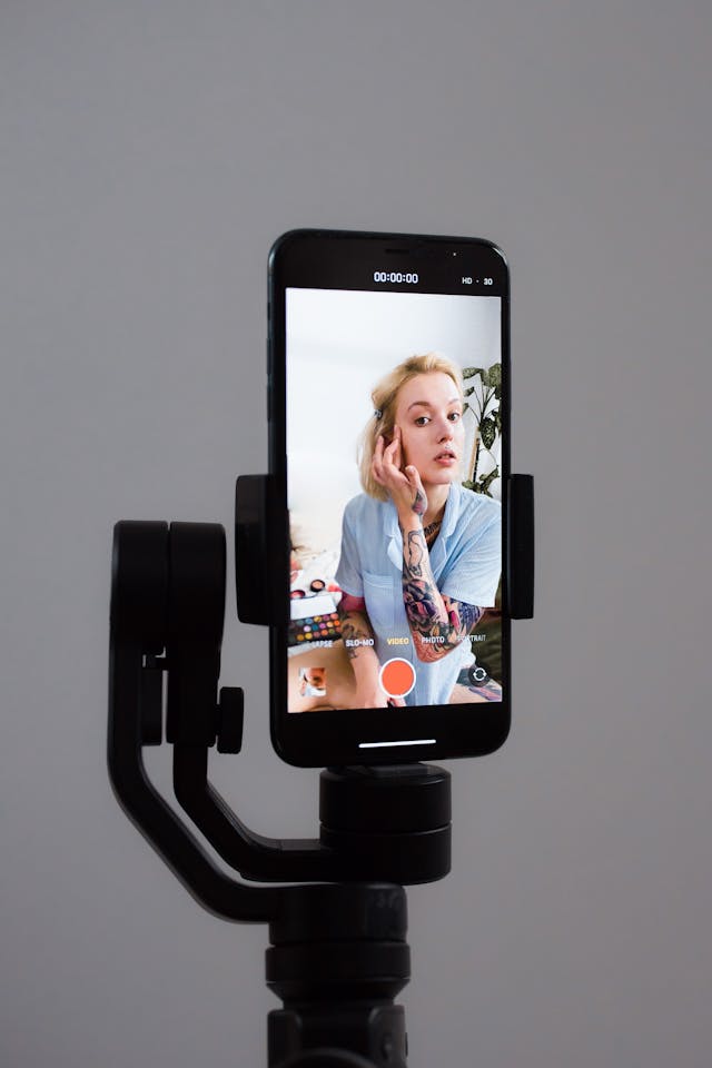 A woman records a makeup tutorial using her front screen.