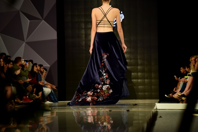 An audience watches a model walk down the runway.